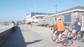 People on beachfront way riding bikes, sport recreation on beach in California.
