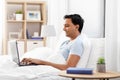 Happy indian man with laptop in bed at home Royalty Free Stock Photo