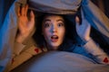 surprised teenage girl under blanket in bed