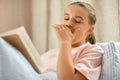 yawning girl reading book in bed at home Royalty Free Stock Photo