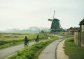 People on bicycles near windmills in Holland Royalty Free Stock Photo