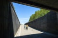 People biking downwards into tunnel under highway