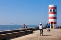 People biking and fishing at the beautiful Porto coast near the Douro river mouth in a sunny early