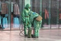 People in bio viral hazard protective suits. Disinfection and decontamination on a public place as a prevention against