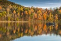 people on boat with autumn foliage with vibrant colors reflecting on the lake in Maryland Royalty Free Stock Photo