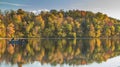 people on boat with autumn foliage with vibrant colors reflecting on the lake in Maryland Royalty Free Stock Photo