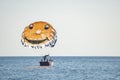 People in boat with open parachute preparing for parasailing on seascape