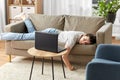 Bored woman with laptop lying on sofa at home Royalty Free Stock Photo