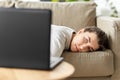 Bored woman with laptop lying on sofa at home