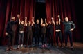 People bowing to audience. Group of actors in dark colored clothes on rehearsal in the theater