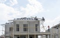 People are building a precast house in construction progress, two workman working on the roof, a worker on the terrace Royalty Free Stock Photo