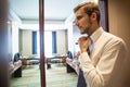 People, business,fashion and clothing concept - close up of man in shirt dressing up and adjusting tie on neck at home. Royalty Free Stock Photo