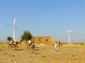 People with camels going through small village in Thar desert in Royalty Free Stock Photo