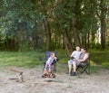 People camping in forest, family active in nature, kindle fire, summer season Royalty Free Stock Photo