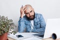 People, career, business and success concept. A portrait of young uccessful bearded bald businessman wearing jean shirt being tire