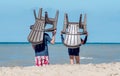 People carry plastic chairs on the beach
