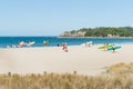 People carrying boards and surf skis across scenic beach to sea