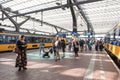 People on a central platform of a railway station with trains on either side