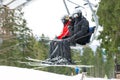 People on the chairlift at the ski resort on a sunny winter day climb up the ski slope