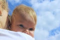 People, childhood, family concept. Cropped shot of a cute baby girl over blue sky background. Sisters hugs.