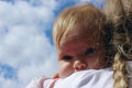 People, childhood, family concept. Cropped shot of a cute baby girl over blue sky background. Sisters hugs.