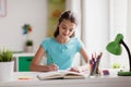 Happy girl with book writing to notebook at home Royalty Free Stock Photo