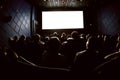 People in the cinema watching a movie. Blank empty white screen. Blurred image