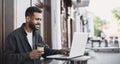 People city lifestyle young man sitting in a cafe using his laptop computer typing keyboard online outside Royalty Free Stock Photo