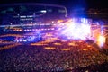 People clapping at night concert, partying and raising hands for the artist on stage. Blurry aerial view of concert crowd