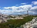 People climbing rocks at famous Peggy's Cove lighthouse, Canada