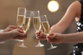 People clinking glasses of champagne against blurred background, closeup. Bokeh effect Royalty Free Stock Photo