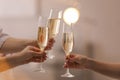 People clinking glasses of champagne against blurred background, closeup. Bokeh effect Royalty Free Stock Photo