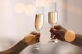 People clinking glasses of champagne against blurred background, closeup. Bokeh effect Royalty Free Stock Photo