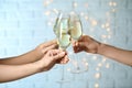 People clinking glasses of champagne against lights, closeup Royalty Free Stock Photo