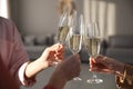 People clinking glasses of champagne in living room, closeup. Holiday cheer and drink Royalty Free Stock Photo