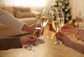 People clinking glasses of champagne in room decorated for Christmas, closeup. Holiday cheer and drink Royalty Free Stock Photo