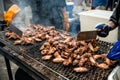 People cooking chicken wings and legs on barbecue grill street food outdoors festival Royalty Free Stock Photo