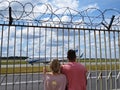 People Couple Guy and Girl in Love Together Looking Watching Planes at Airport through Fence with Barbed Wire