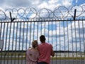 People Couple Guy and Girl in Love Together Looking Watching Planes at Airport through Fence with Barbed Wire