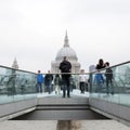 People cross river thames on millennium bridge with st paul`s ca Royalty Free Stock Photo