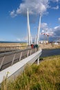 People crossing the Passerelle du Grand Large - Large Bridge - in Dunkirk on a sunny day with the town in the background