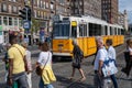 People crossing the street in front of a yellow streetcar