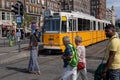 People crossing the street in front of a yellow streetcar