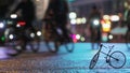 People cyclists, blurred illuminated night city street against background of small scale model of bicycle