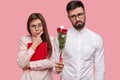 People, dating and relationship concept. Displeased bearded man in white elegant shirt gives girlfriend roses, wants to
