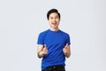 People different emotions, lifestyle and casual concept. Cheerful upbeat asian man in blue t-shirt, pointing fingers up