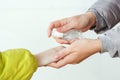 People disinfecting hands with antiseptic spray outdoors. Mother and son using sanitizer spray for hands