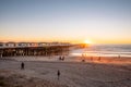 People doing activities at the beach near the pier with beautiful sunset