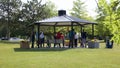 People doing morning stretch exercise under a pavilion on a hot summer day