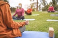 People doing yoga class outdoor sitting on grass while wearing safesty masks during coronavirus outbreak - Social distance and Royalty Free Stock Photo